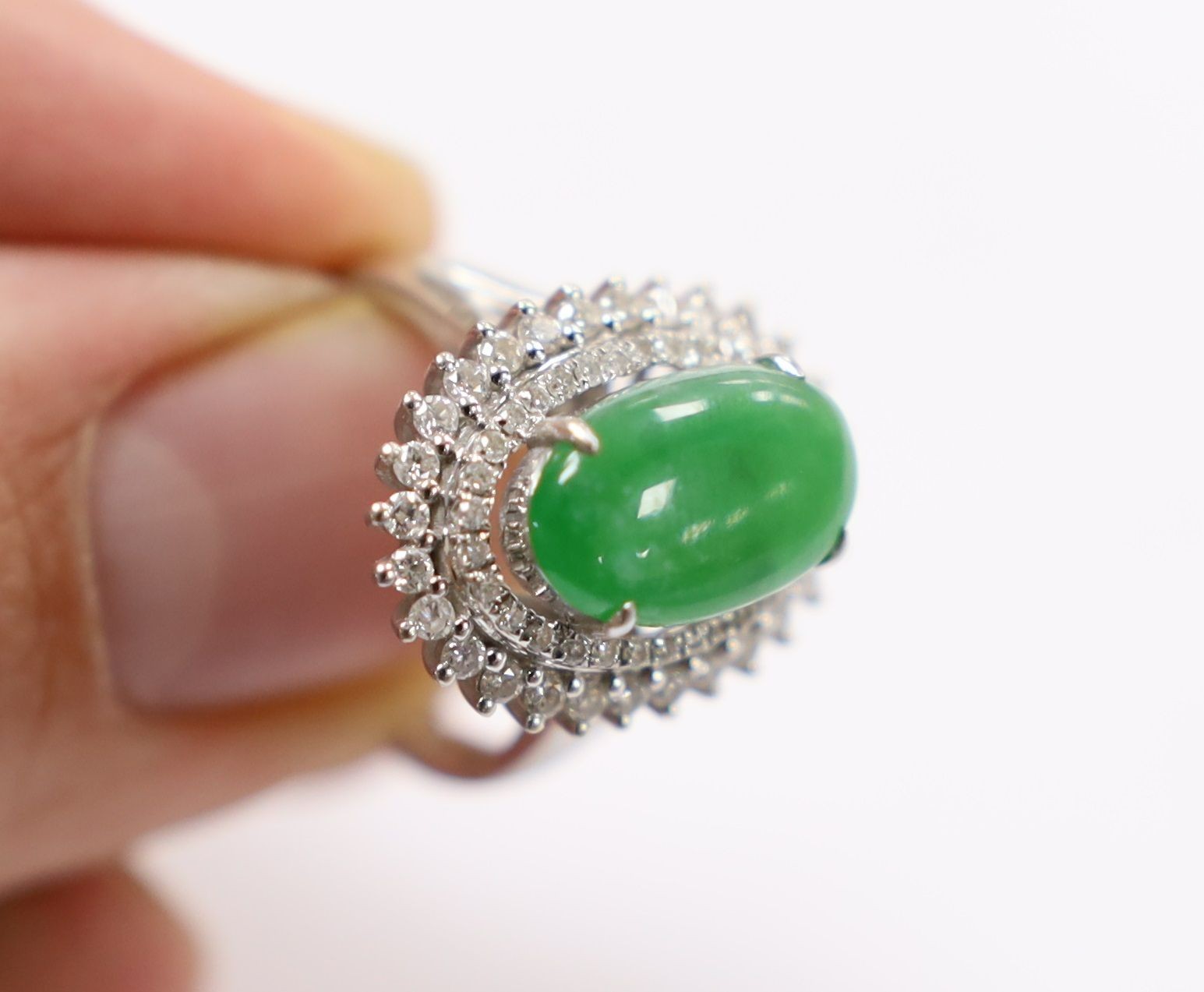 A modern 18k white metal, cabochon jade and two row diamond chip set oval cluster ring size L, gross weight 6.4 grams.